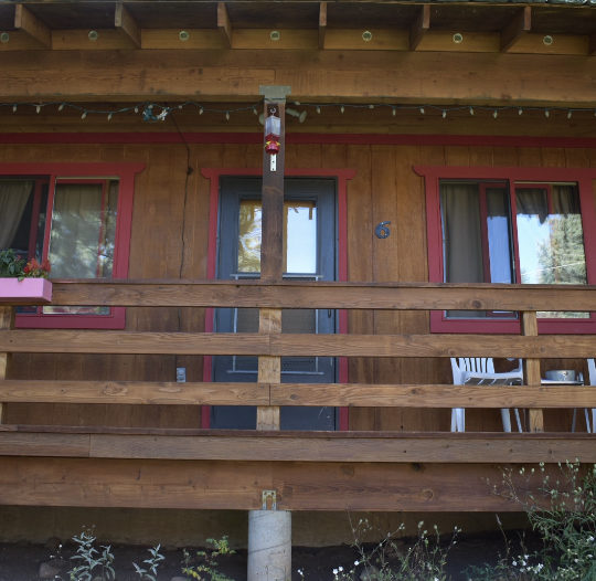 Cozy wooden front porch with balcony and chair, perfect for relaxing outdoors.