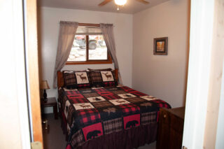 Relaxing bed with plaid quilt by a window, perfect spot for enjoying a peaceful morning view.