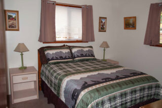Cozy bed with green and gray plaid comforter, perfect for a relaxing stay.